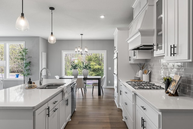 kitchen with stainless steel appliances, a sink, custom exhaust hood, decorative backsplash, and white cabinets
