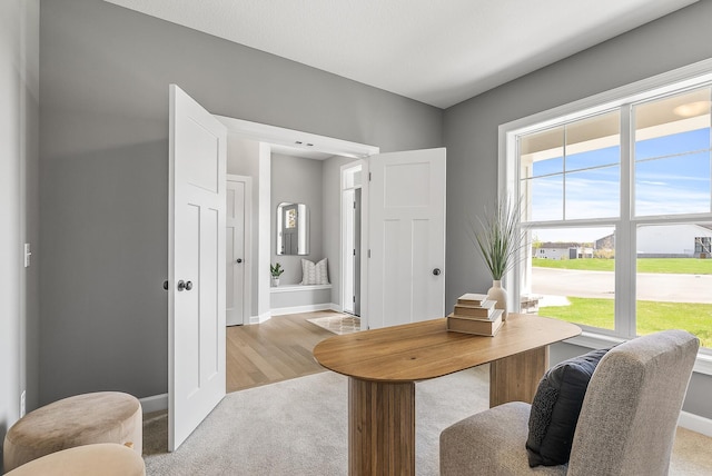home office featuring light carpet, healthy amount of natural light, and baseboards