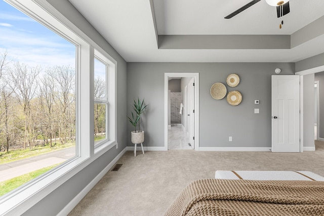 carpeted bedroom with multiple windows, baseboards, connected bathroom, and a raised ceiling