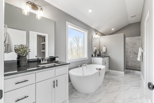 full bathroom featuring marble finish flooring, walk in shower, vaulted ceiling, a freestanding tub, and two vanities