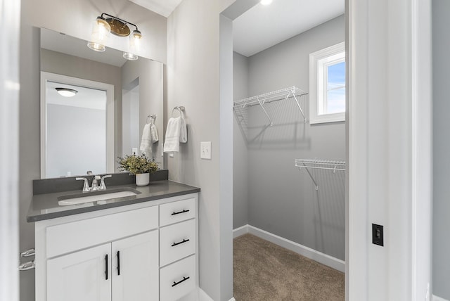 bathroom featuring a spacious closet, vanity, and baseboards