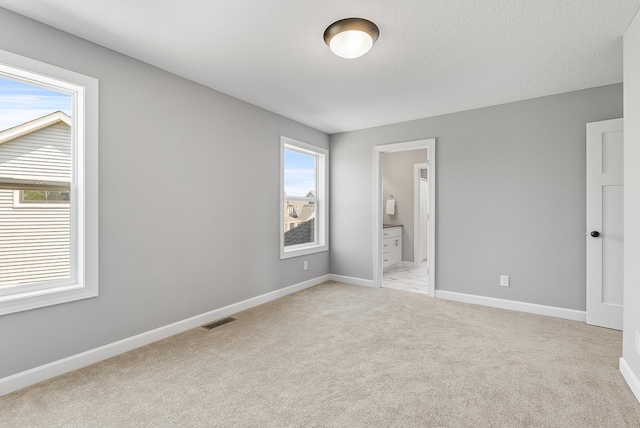 unfurnished bedroom featuring light colored carpet, baseboards, and connected bathroom