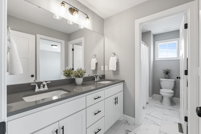 bathroom featuring baseboards, marble look tiles, double vanity, and toilet
