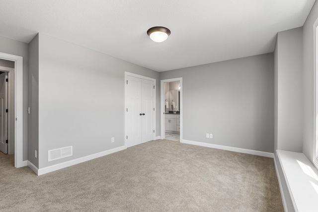 unfurnished bedroom featuring carpet, baseboards, and ensuite bath