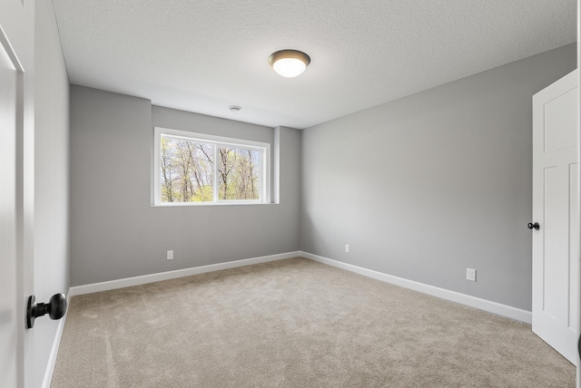 empty room with carpet floors, baseboards, and a textured ceiling