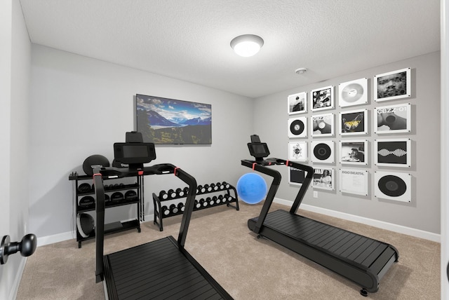 workout area with carpet floors, a textured ceiling, and baseboards