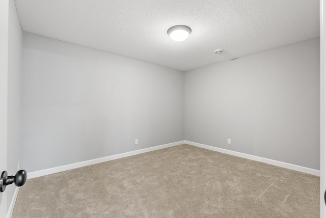 carpeted spare room featuring a textured ceiling and baseboards