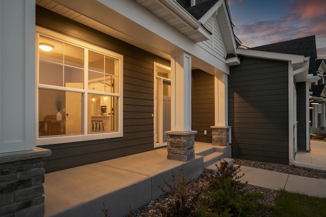 property exterior at dusk featuring a porch and a shingled roof