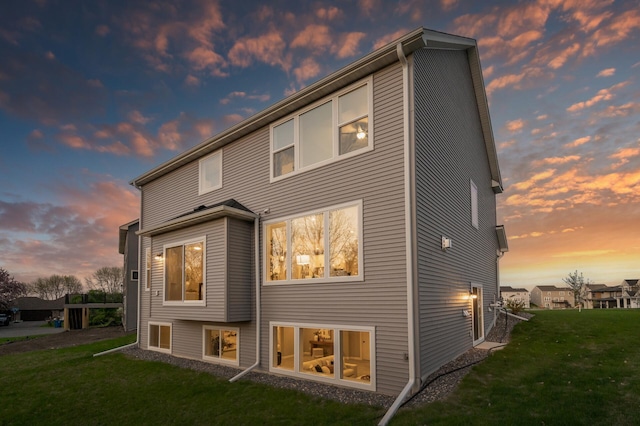 back of house at dusk with a lawn