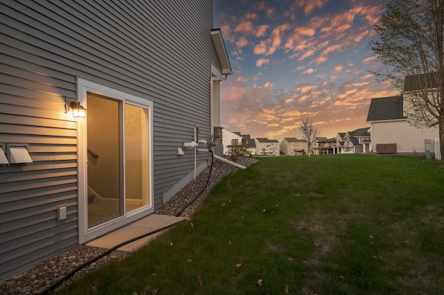 property exterior at dusk featuring a lawn and a residential view