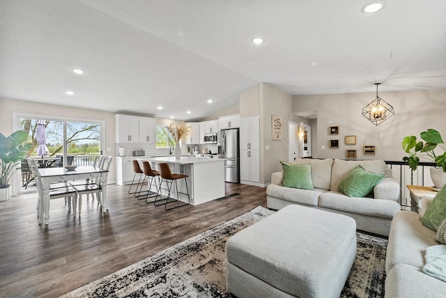 living area featuring dark wood-style flooring, a notable chandelier, recessed lighting, and vaulted ceiling