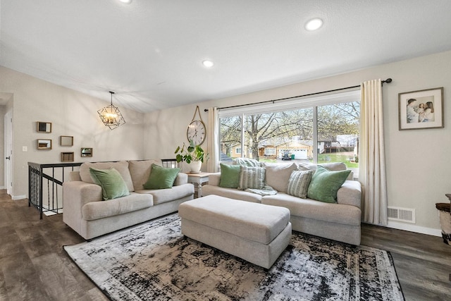 living area with an inviting chandelier, baseboards, visible vents, and dark wood finished floors