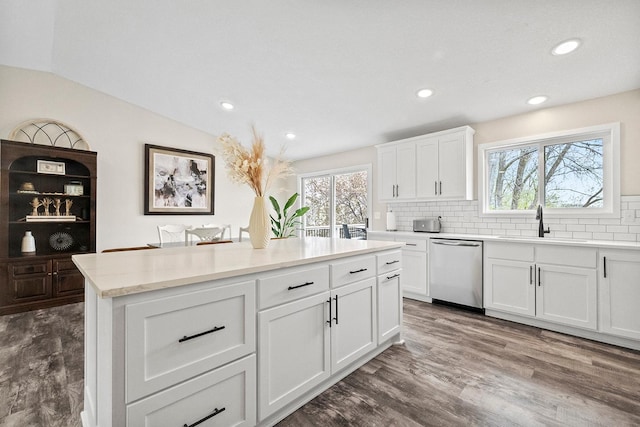 kitchen with a sink, tasteful backsplash, white cabinets, stainless steel dishwasher, and a kitchen island