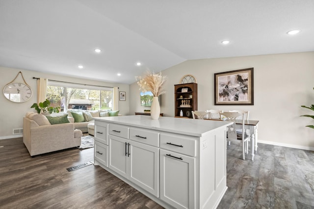 kitchen with a center island, white cabinetry, dark wood-type flooring, light countertops, and lofted ceiling