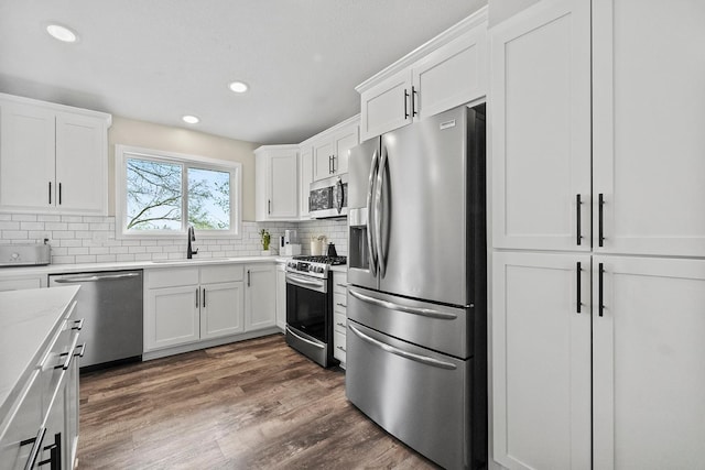kitchen featuring white cabinetry, decorative backsplash, appliances with stainless steel finishes, and a sink