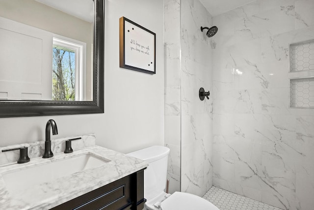 bathroom with toilet, a marble finish shower, and vanity