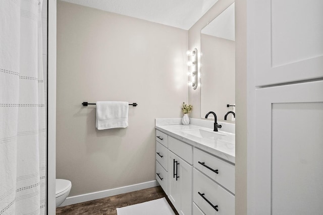 bathroom featuring baseboards, vanity, toilet, and wood finished floors
