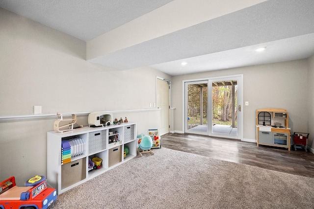 playroom featuring wood finished floors, a textured ceiling, recessed lighting, carpet flooring, and baseboards