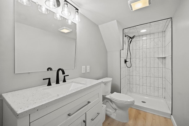 bathroom featuring vanity, toilet, tiled shower, and wood finished floors