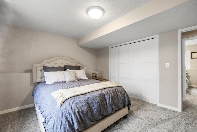 carpeted bedroom with a closet, a textured ceiling, and baseboards