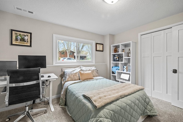 carpeted bedroom with a textured ceiling, a closet, and visible vents