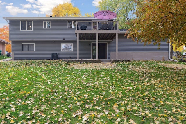 rear view of property with central AC unit, a balcony, and a lawn