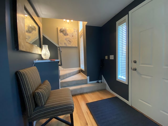 entrance foyer with an inviting chandelier, baseboards, stairs, and wood finished floors