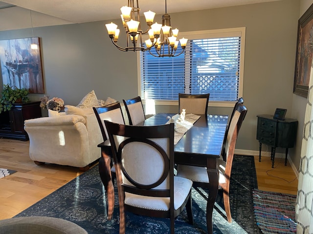 dining space featuring an inviting chandelier, baseboards, and wood finished floors