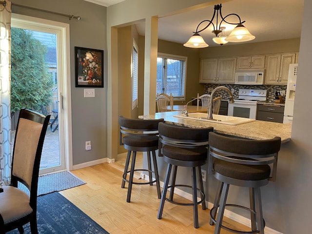 kitchen featuring plenty of natural light, a sink, light wood-style flooring, and white appliances