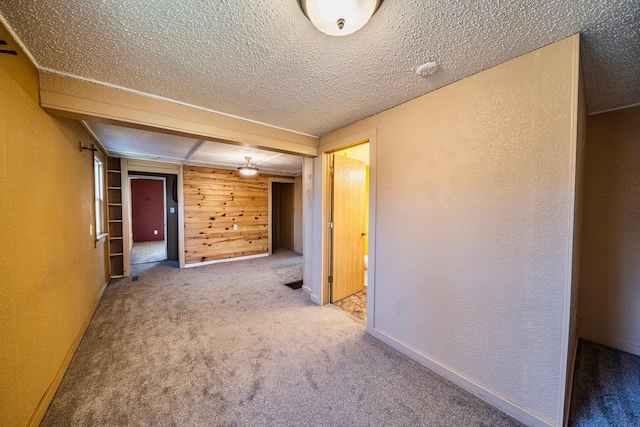 carpeted empty room featuring a textured ceiling and a textured wall
