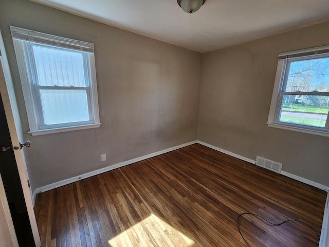 empty room featuring baseboards, hardwood / wood-style flooring, and visible vents