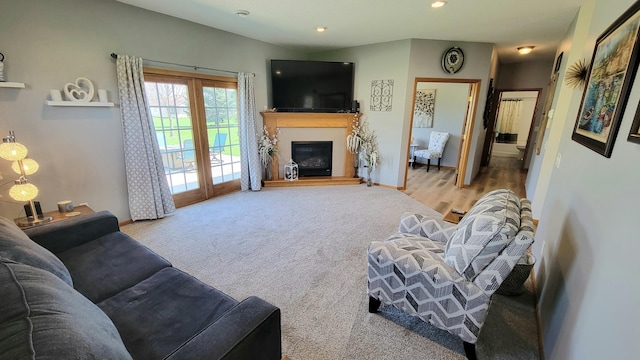 carpeted living area featuring recessed lighting, baseboards, and a glass covered fireplace