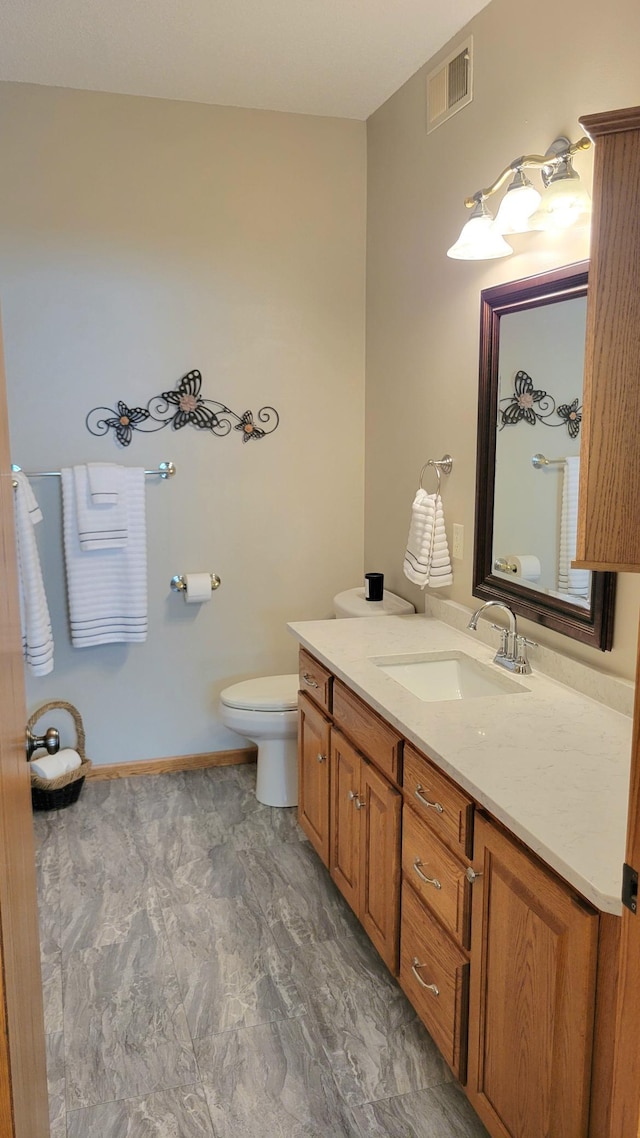 bathroom featuring visible vents, baseboards, toilet, and vanity