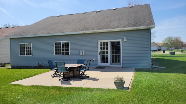 rear view of house featuring a lawn, a patio, and roof with shingles