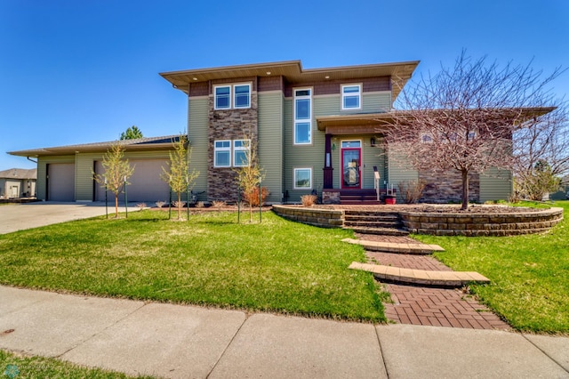 prairie-style house featuring an attached garage, driveway, a front lawn, and stone siding