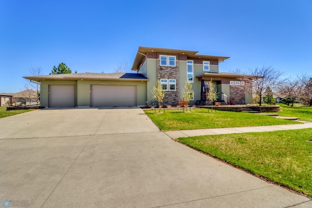 prairie-style house with concrete driveway, stone siding, an attached garage, and a front yard