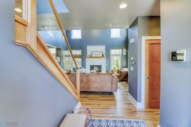 foyer entrance with light wood-style floors, baseboards, and a glass covered fireplace
