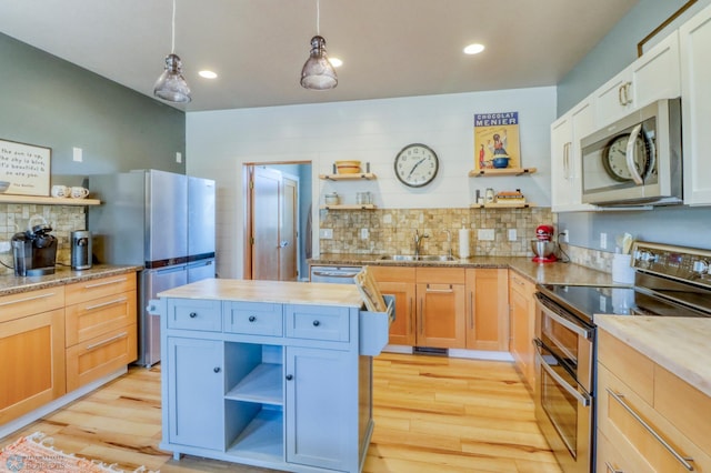 kitchen with a sink, appliances with stainless steel finishes, open shelves, and wood counters