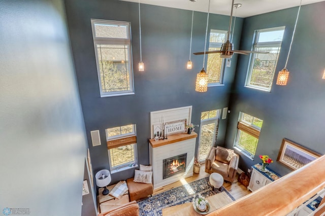 living room featuring a high ceiling, a glass covered fireplace, and wood finished floors