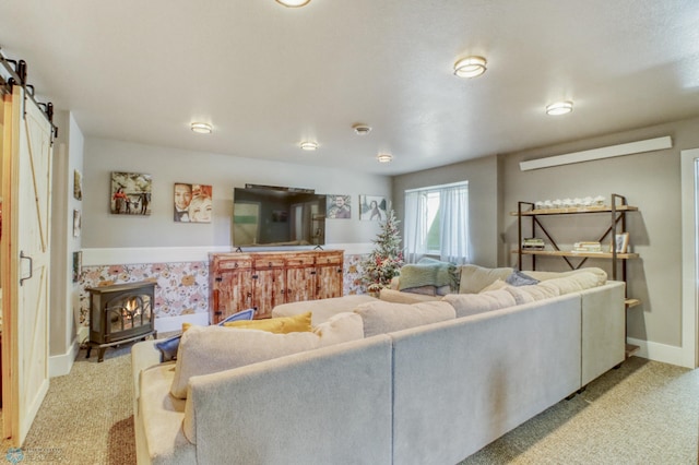 living room featuring baseboards, a wood stove, a barn door, and light carpet