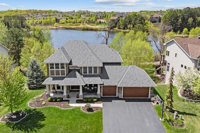 view of front of home featuring a shingled roof, a water view, stone siding, and a front yard