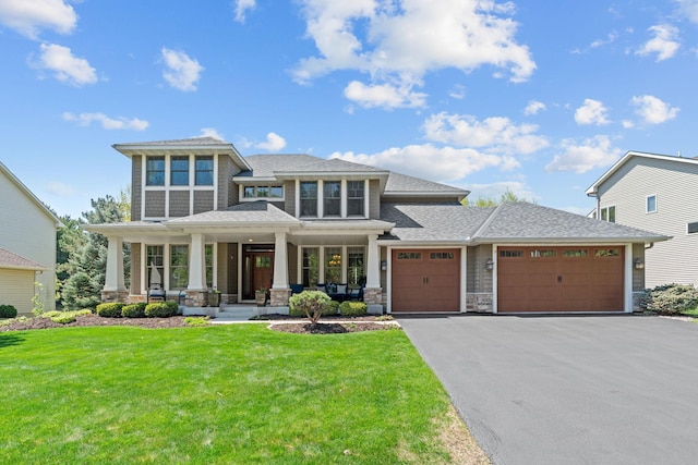 prairie-style home featuring an attached garage, a porch, a front lawn, driveway, and roof with shingles