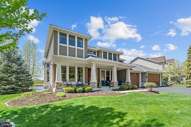 view of front facade featuring a porch, an attached garage, a front lawn, and asphalt driveway