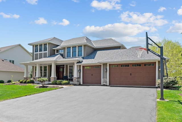 view of front of property with covered porch, an attached garage, a front lawn, driveway, and a shingled roof