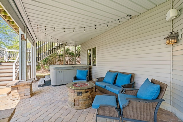 view of patio / terrace with a hot tub, stairs, and an outdoor fire pit
