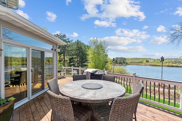 wooden terrace with outdoor dining area, a water view, and grilling area