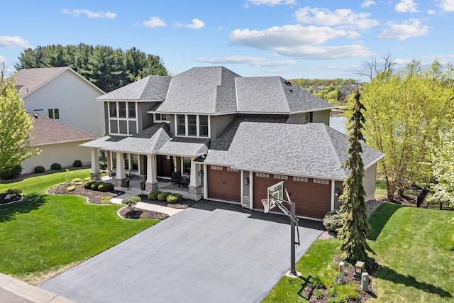 view of front of property featuring a porch, roof with shingles, asphalt driveway, and a front lawn