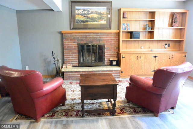living area featuring wood finished floors and a brick fireplace