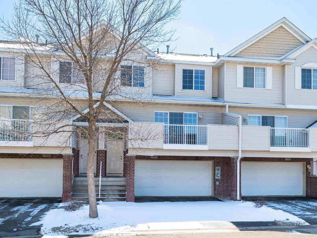 townhome / multi-family property with an attached garage and brick siding