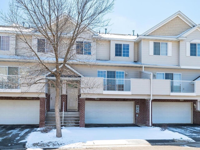 townhome / multi-family property with an attached garage and brick siding